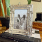Decorative silver picture frame with a photo of two people on top of a Vogue book.