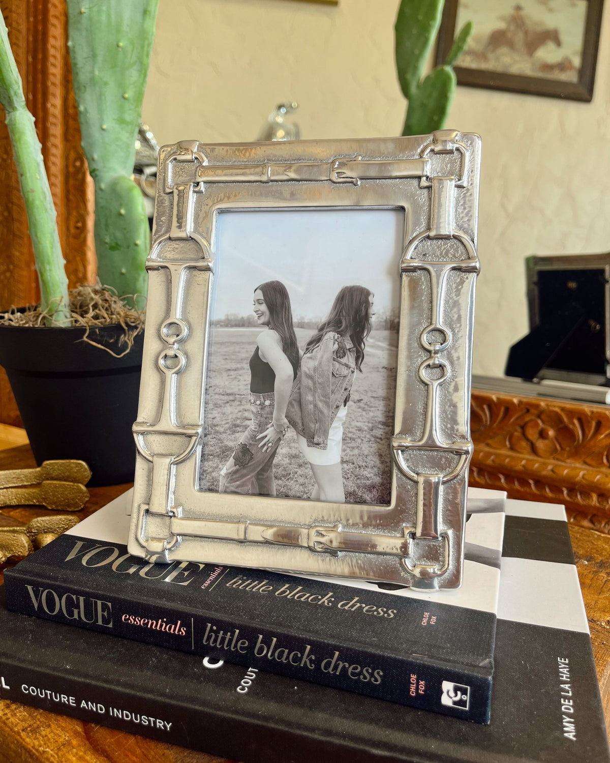 Decorative silver picture frame with a photo of two people on top of a Vogue book.