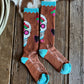Pair of brown socks with colorful designs and blue toes on a wooden surface.