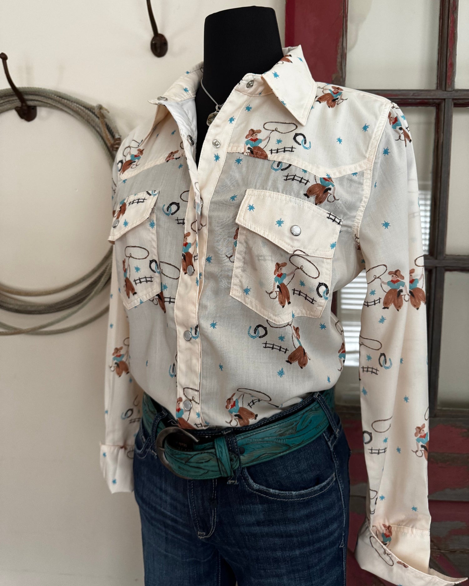 Mannequin wearing a patterned shirt with cartoon characters and jeans, standing indoors.
