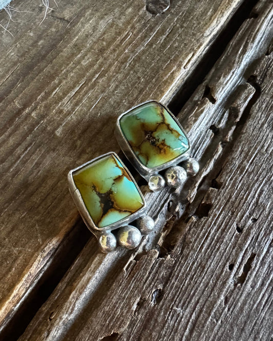 Pair of earrings with turquoise stones on a wooden surface