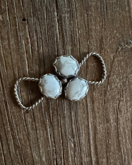 Silver twilly slide with three hexagonal stones on a wooden surface