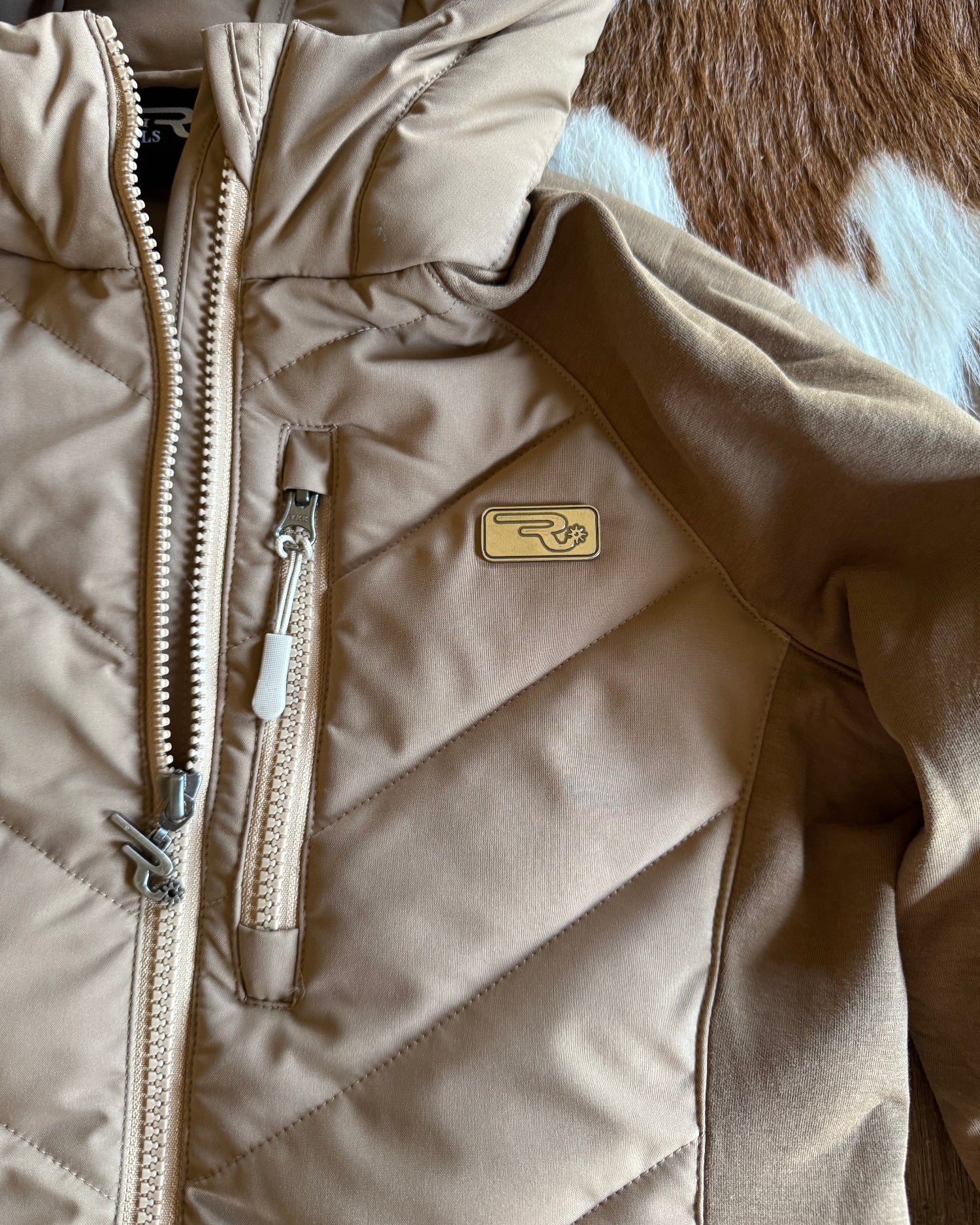 Beige quilted jacket with a brand logo on a textured surface