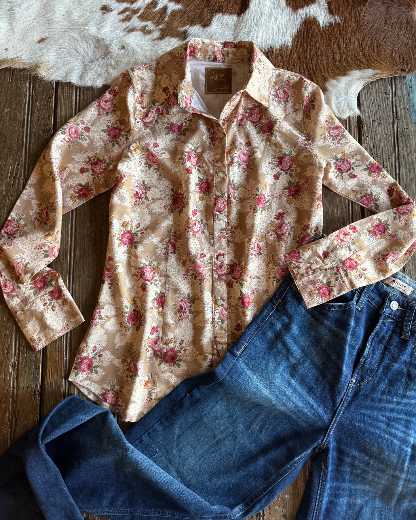 Floral shirt and denim jeans on a wooden surface with cowhide rug