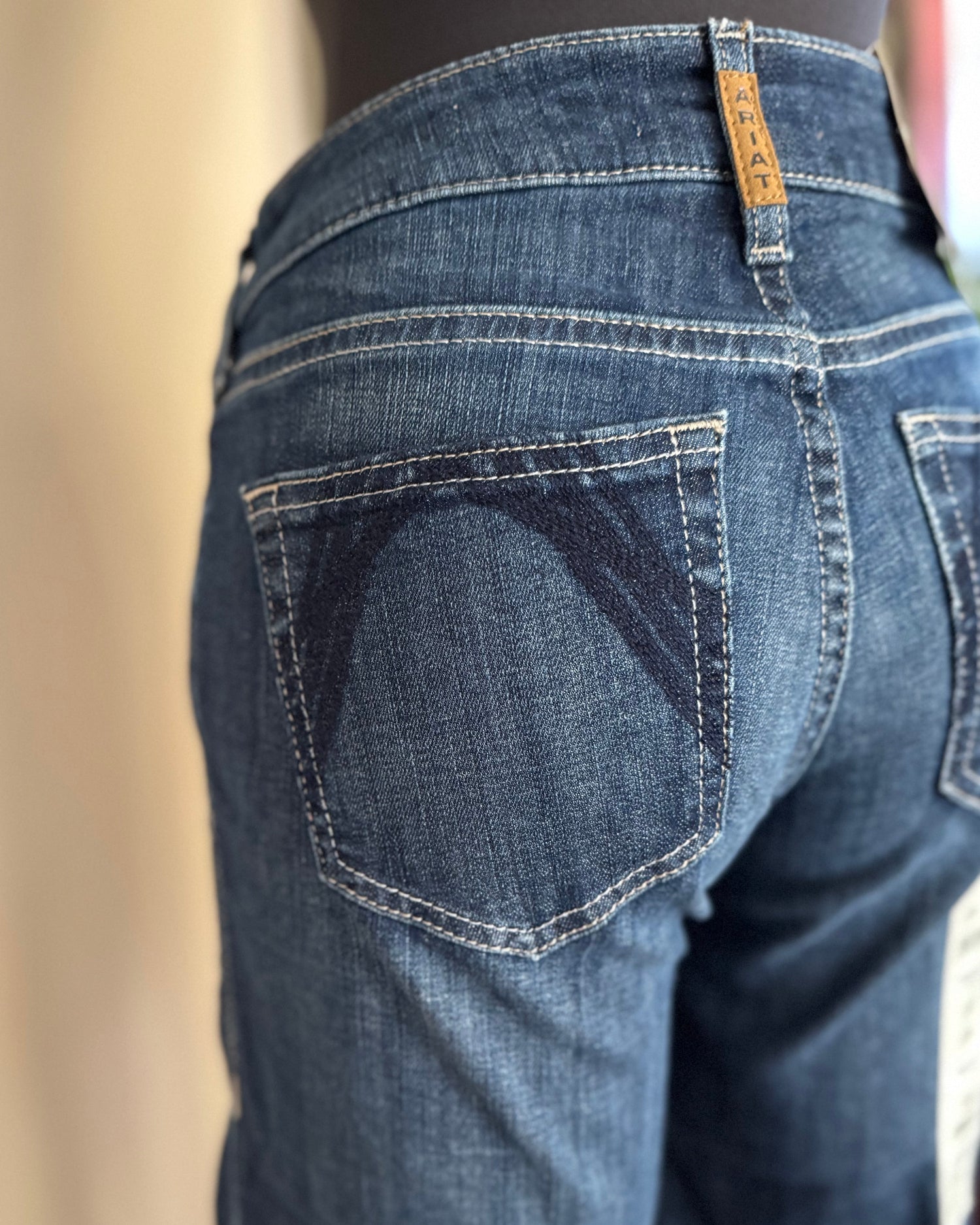Blue jeans with a visible brand tag on the back pocket against a neutral background