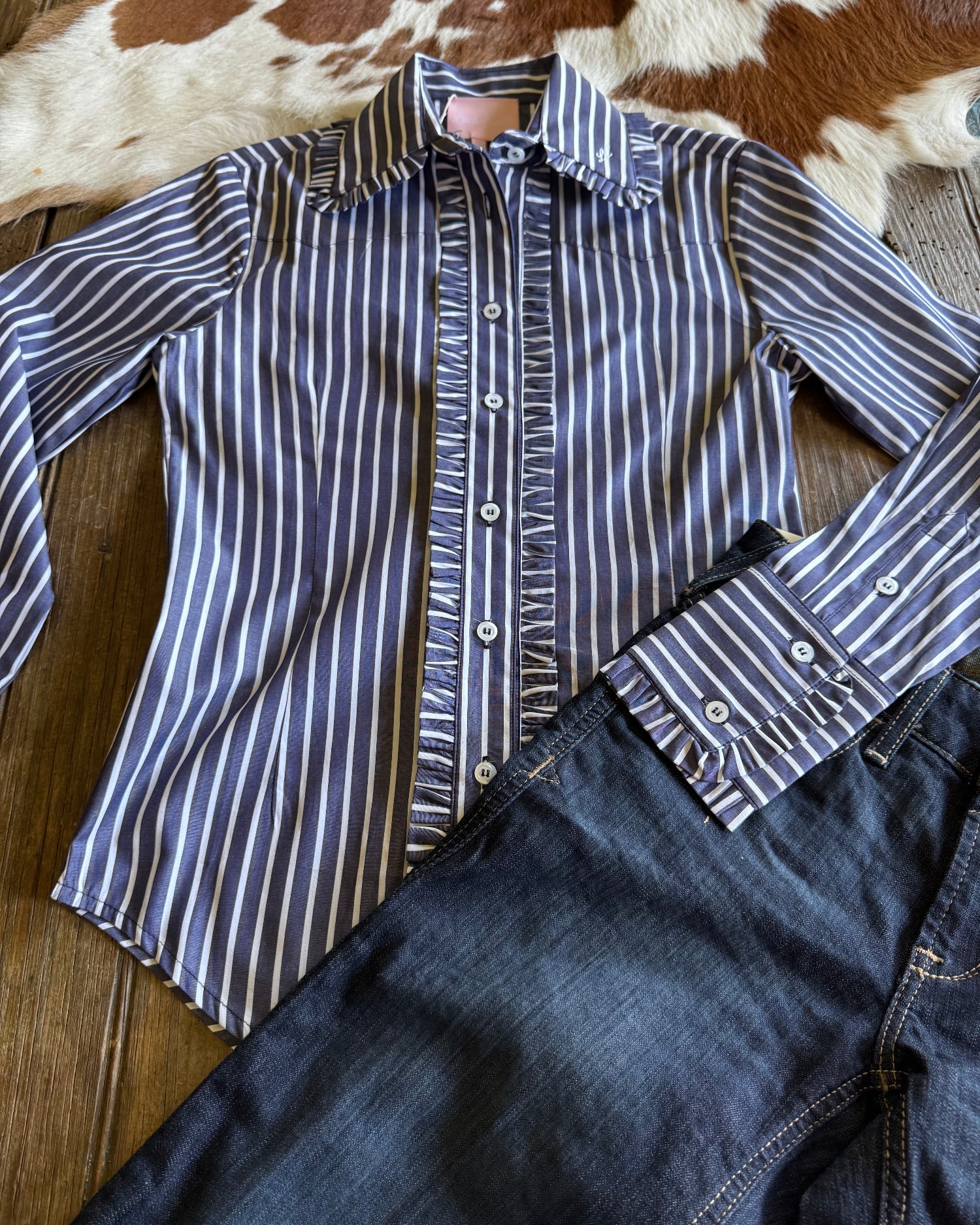 Flat lay of Ivy Pinstripe Frill Shirt with jeans on rustic wood background