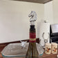 Wine bottle with a silver horse-shaped stopper on a wooden surface.
