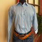 Person wearing a blue striped shirt and jeans with a brown belt, standing indoors.