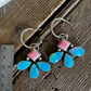 Butterfly-shaped earrings with pink and blue wings on a wooden surface with a ruler for scale.