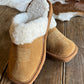 Brown slippers with white fur lining on a wooden surface