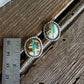 Pair of earrings on a wooden surface with a ruler for scale.