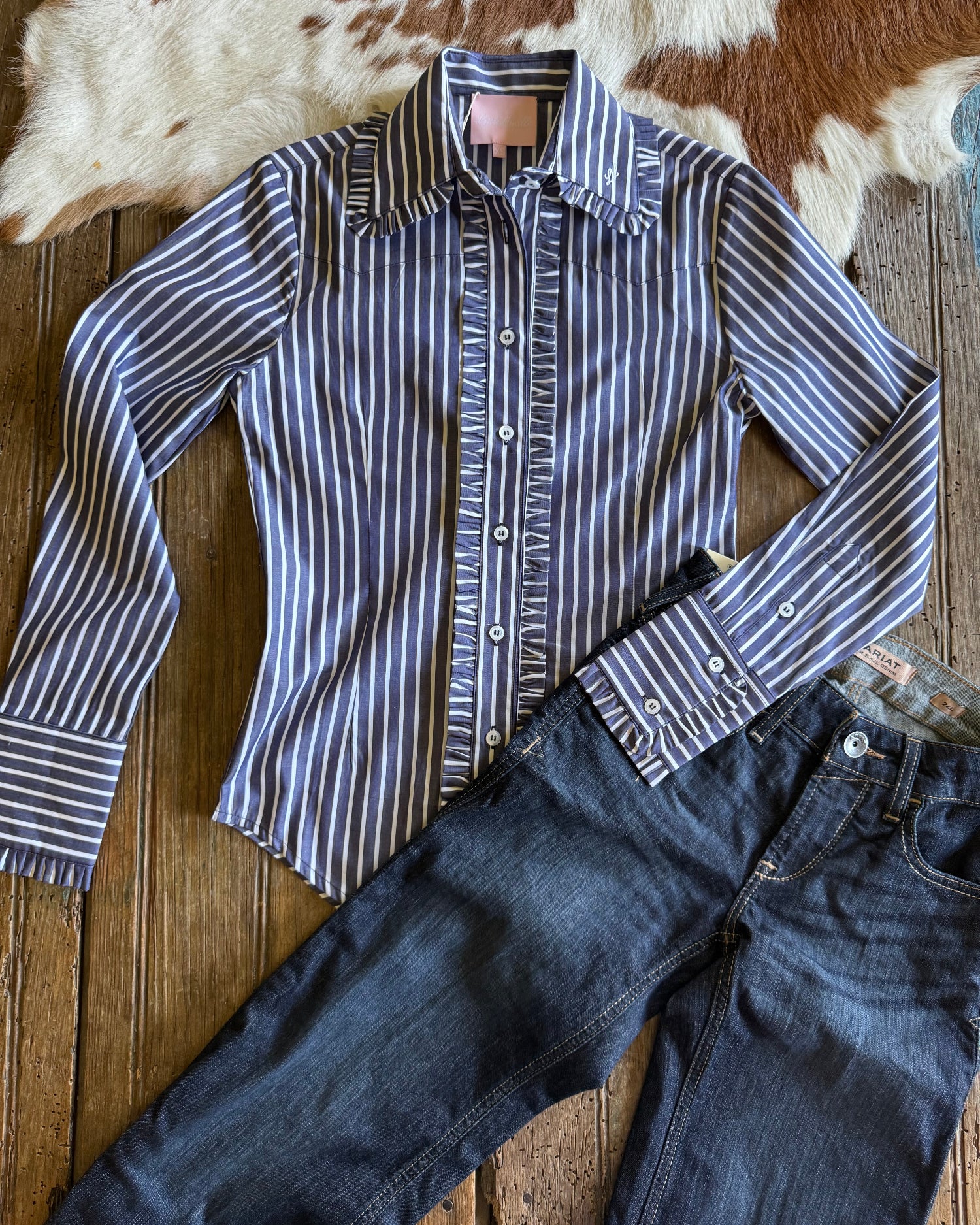 Flat lay of Ivy Pinstripe Frill shirt on rustic wood and cowhide background 