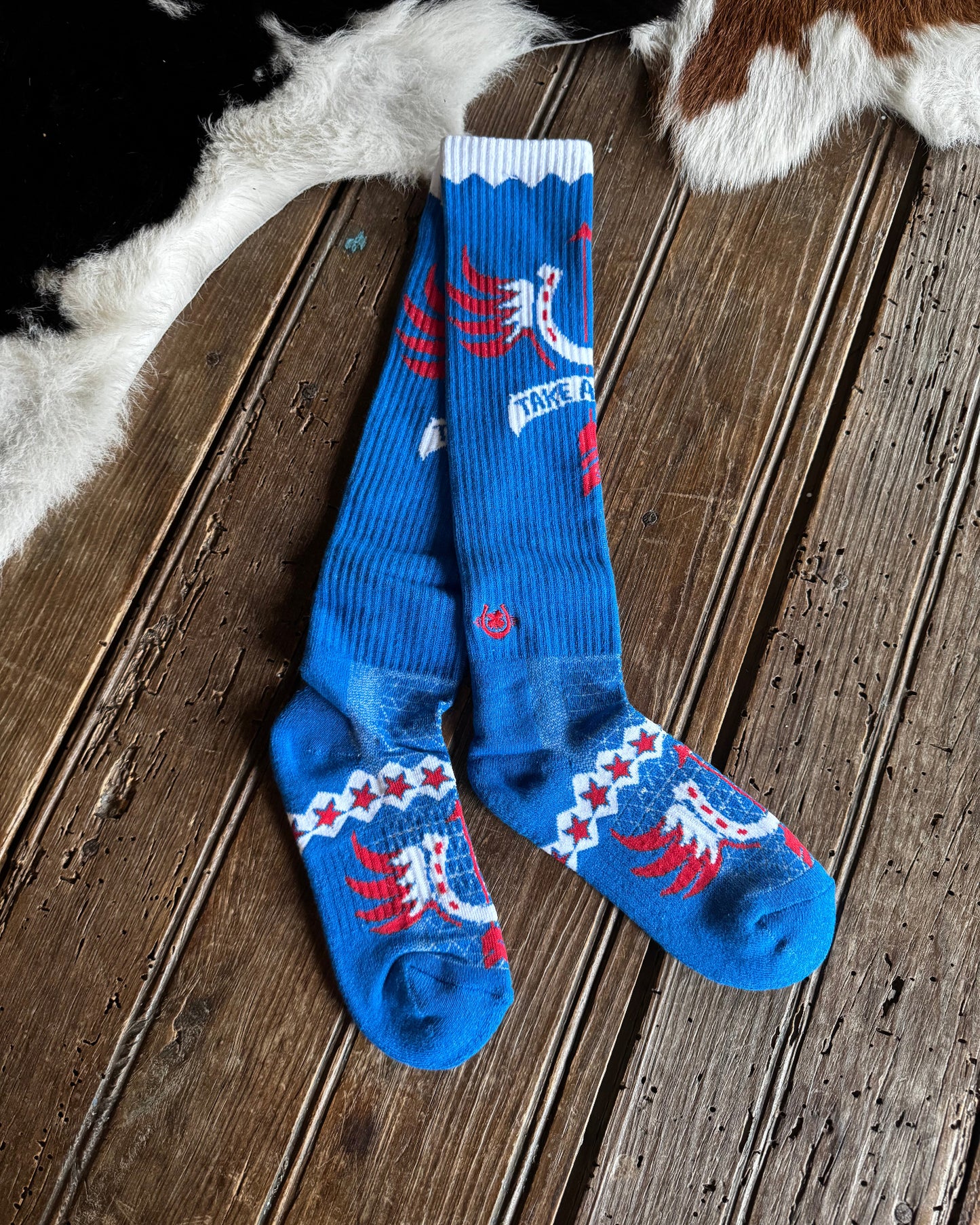 Blue socks with red and white designs on a wooden floor.