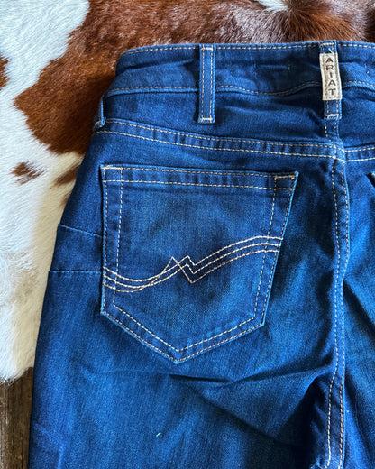 Close-up of blue jeans with a brand label on a cowhide rug