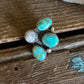 Turquoise ring with white stones on a wooden surface