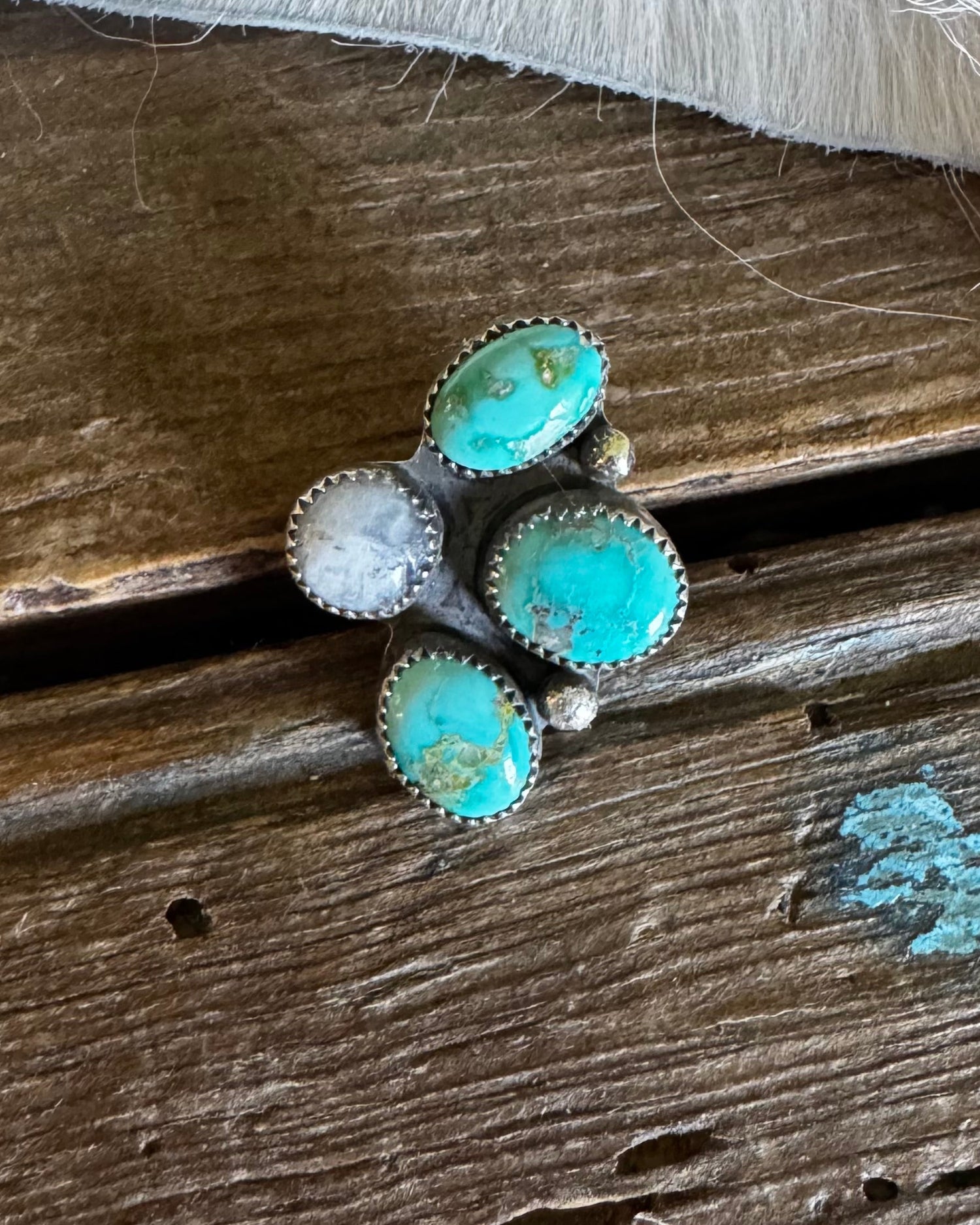 Turquoise ring with white stones on a wooden surface