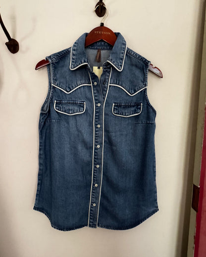 Folded denim shirt on a white surface with a hanger.