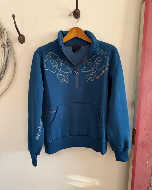 Blue hoodie with floral embroidery on a wooden hanger against a white wall.