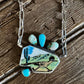 Necklace with a paw-shaped pendant featuring a bird design on a wooden surface