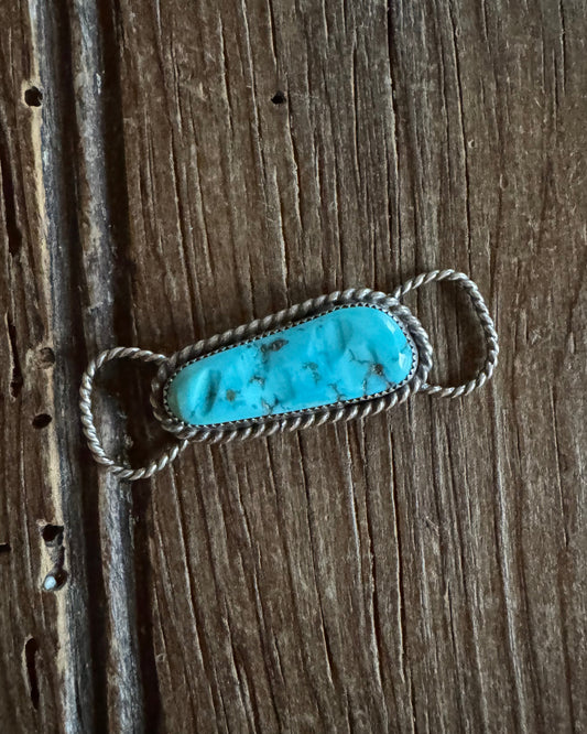 Turquoise stone twilly slide on a wooden surface