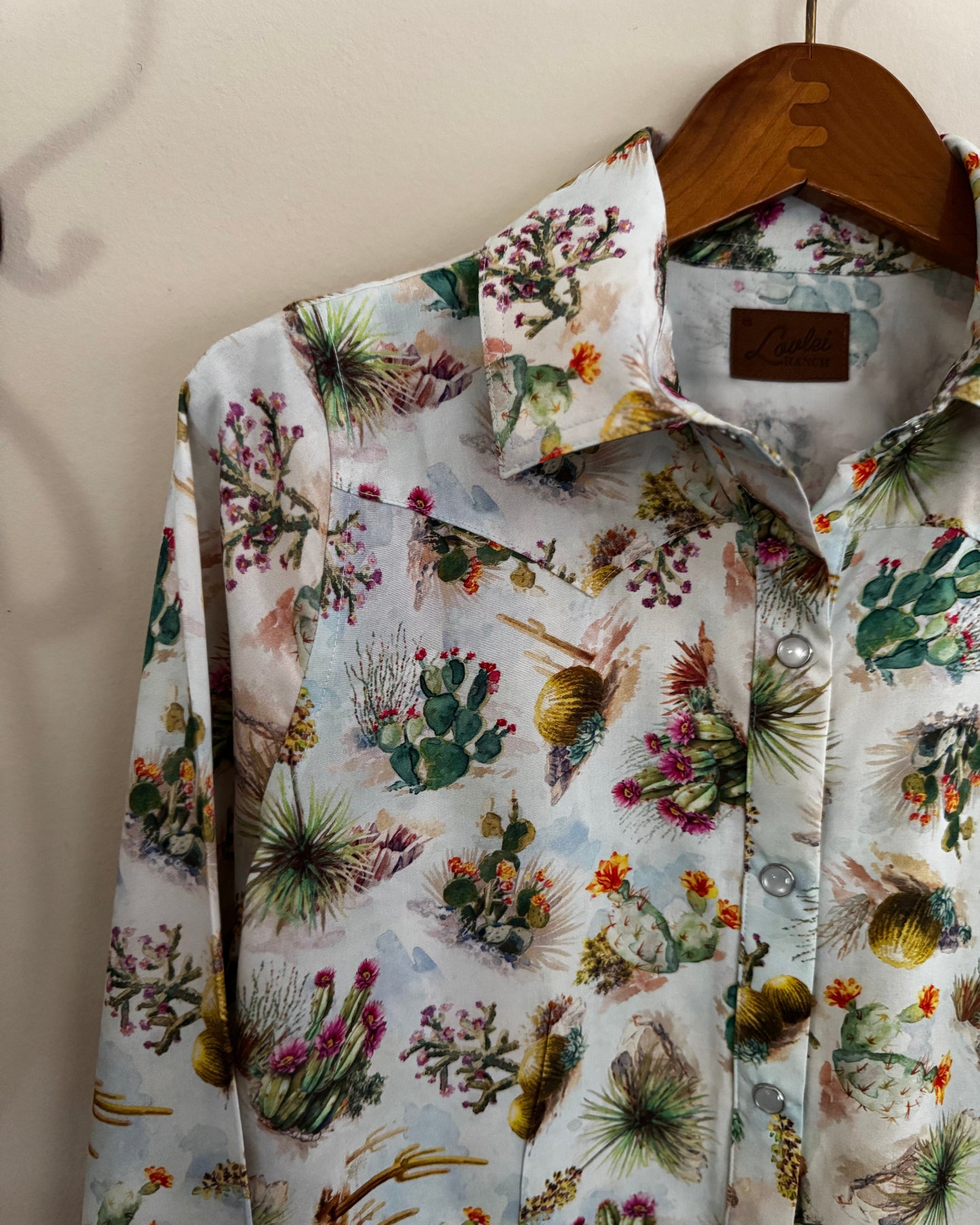 Floral patterned shirt on a hanger against a neutral background