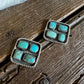 Pair of square earrings with turquoise stones on a wooden surface