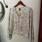 Folded floral-patterned garment on a hanger against a white background