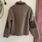 Gray fleece jacket with black patches hanging on a wall