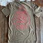 Green t-shirt with red graphic design on a wooden surface with cowhide rug