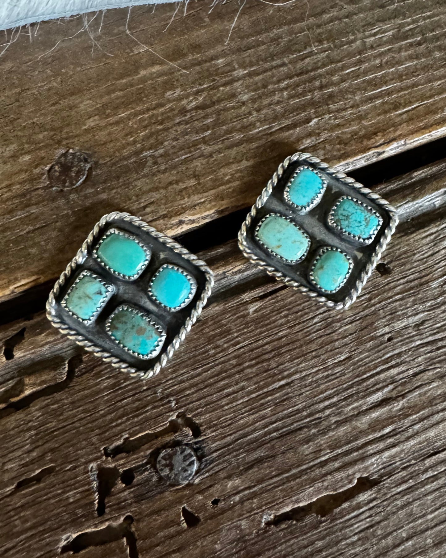 Pair of turquoise stone earrings on a wooden surface