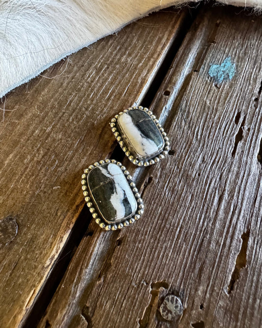 Pair of earrings with stone and gold accents on a wooden surface