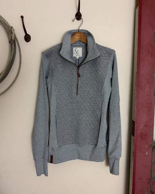 Gray hoodie on a white surface with a blurred background