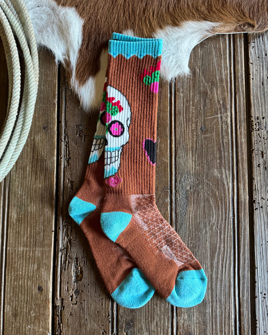 Sock with colorful design on a wooden surface next to a cowhide rug
