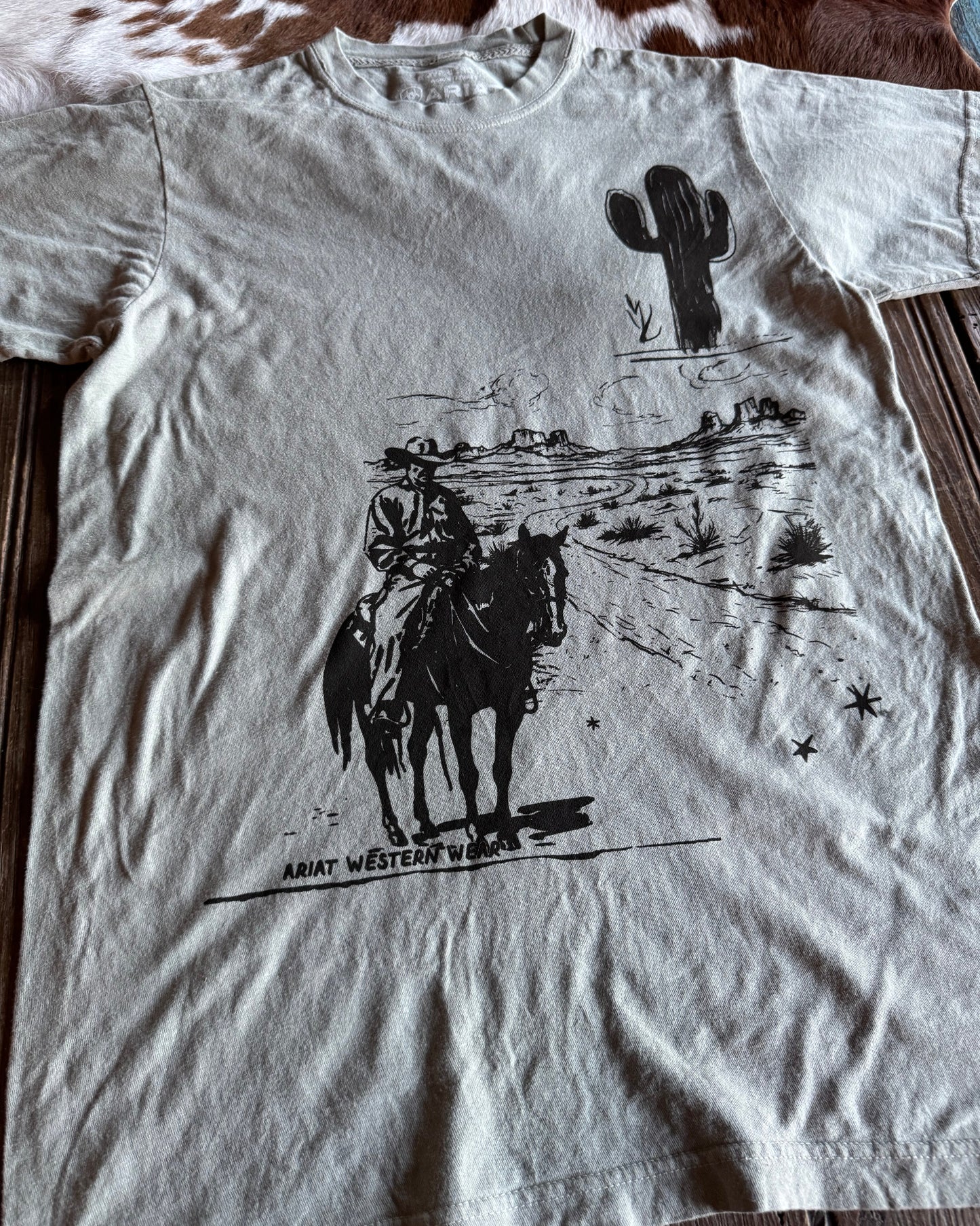 White t-shirt with black graphic design on a wooden surface