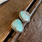 Turquoise stone earrings on a wooden surface with fur in the background
