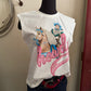 White t-shirt with a graphic of a cowboy and horse on a mannequin against a beige wall.