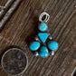 Turquoise stone pendant on a wooden surface with a coin for scale