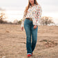 Model standing in a field, dressed in a stylish modern western outfit.