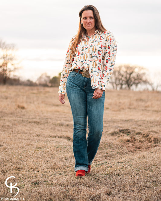 Model standing in a field, dressed in a stylish modern western outfit.