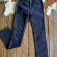 Dark blue jeans on a wooden surface with a cowhide rug in the background