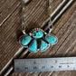 Turquoise pendant necklace on a wooden surface with a ruler for scale.