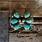 Pair of turquoise earrings on a wooden surface with a ruler for scale.