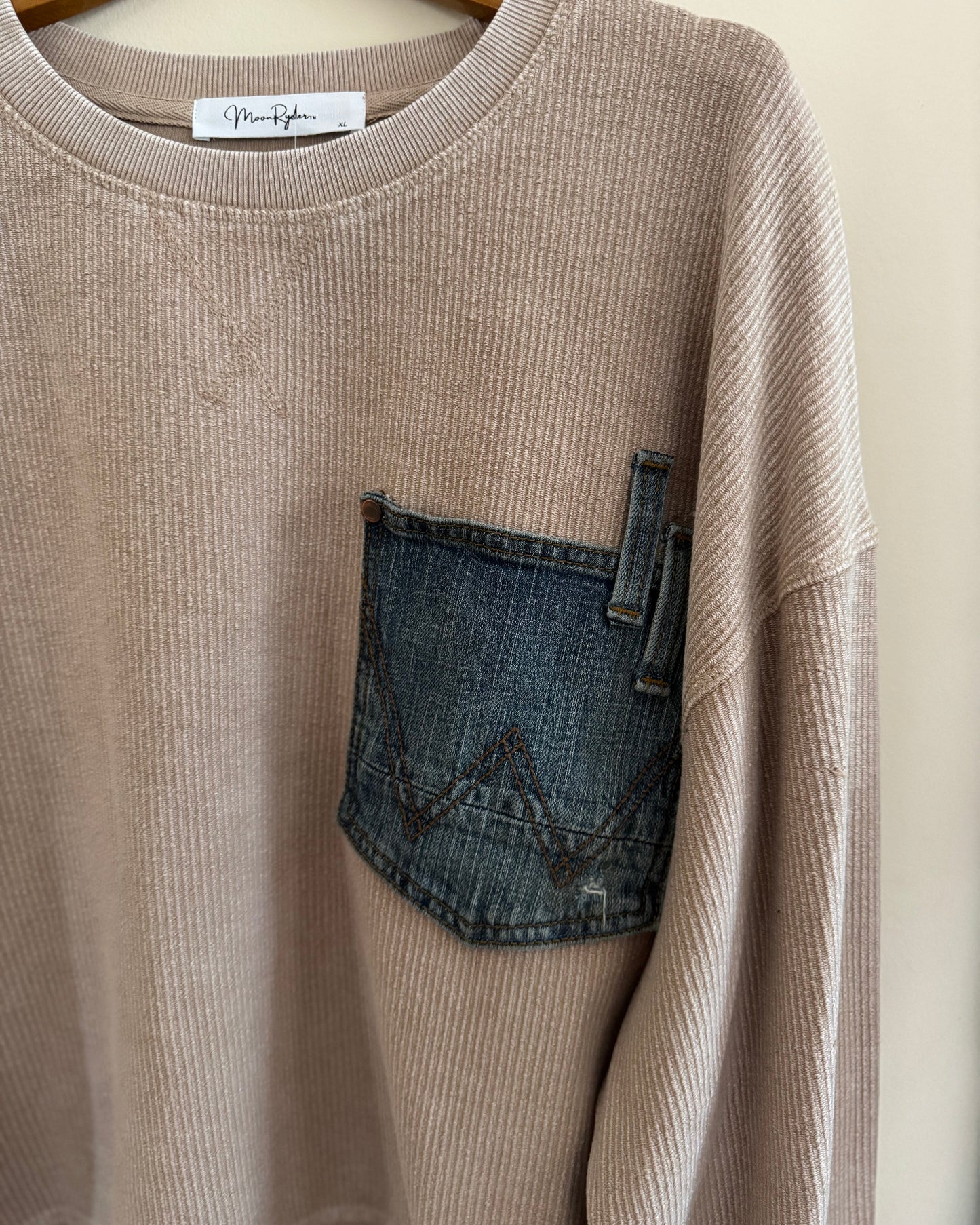 Beige sweater with a denim pocket and 'MoonRyder' label on a white background