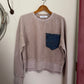 Brown sweater with a blue pocket on a white surface