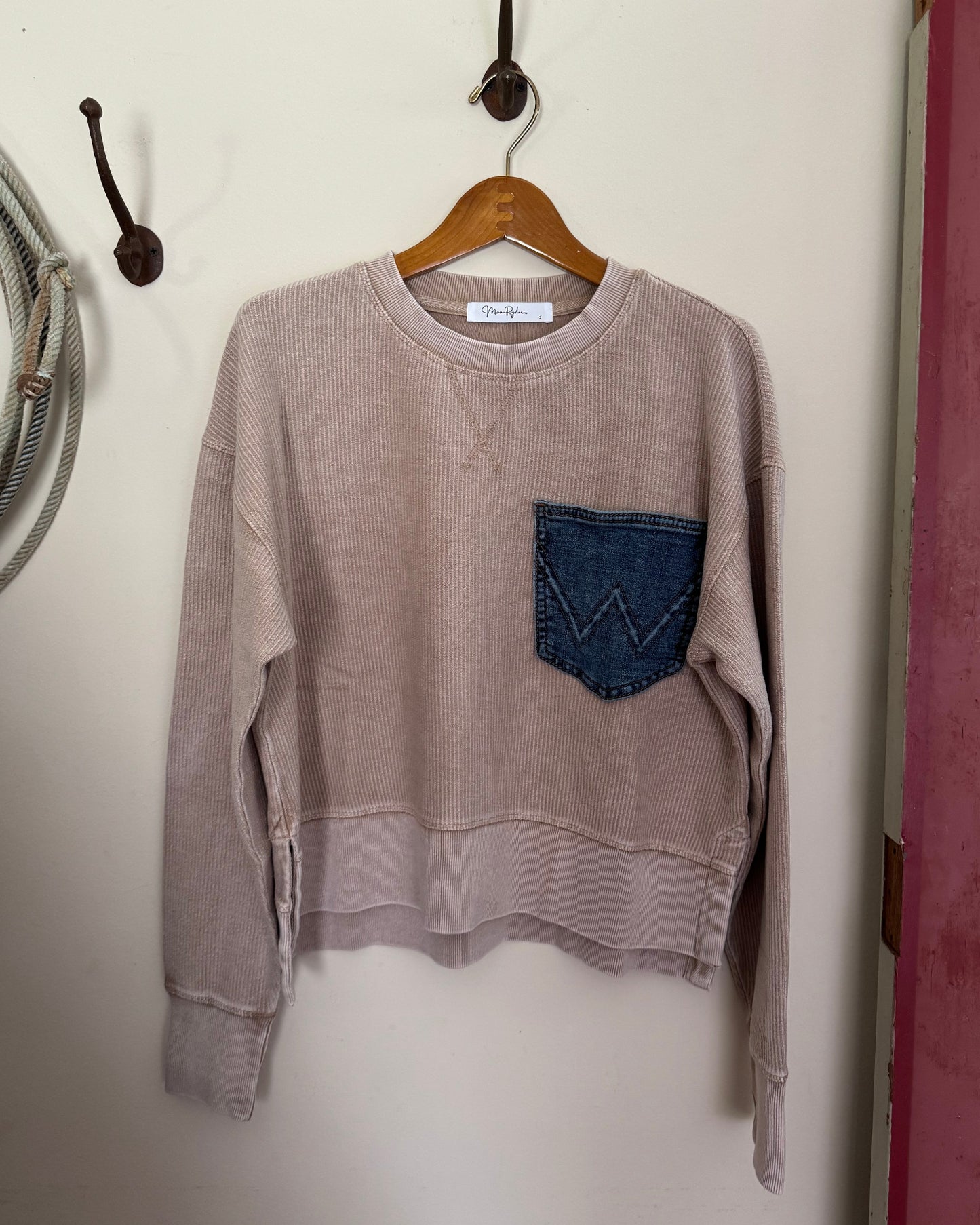 Brown sweater with a blue pocket on a white surface