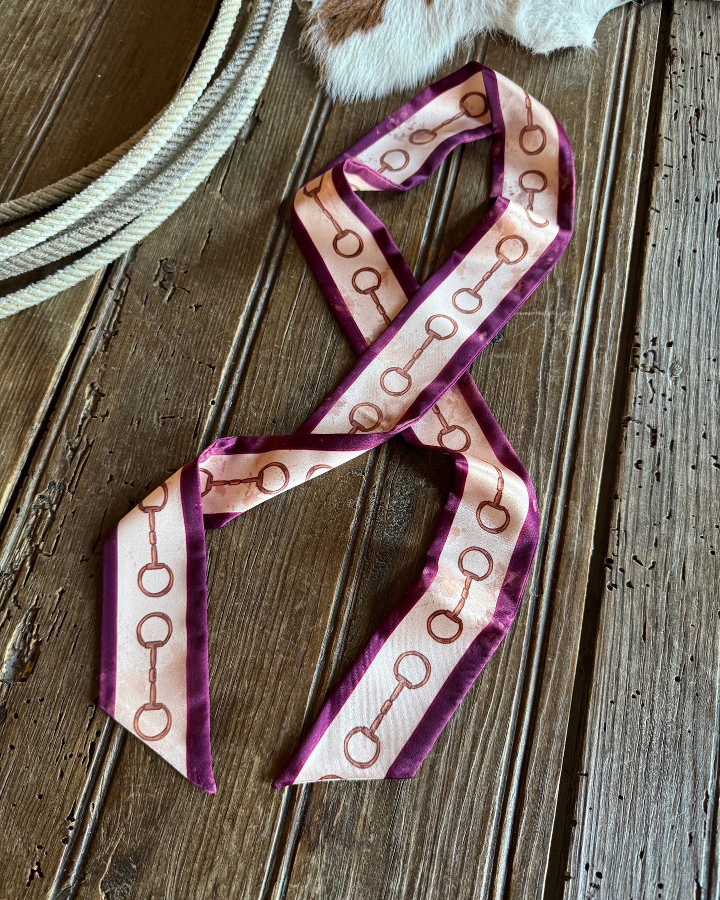 Twilly scarf featuring snaffle bits on a wooden background with a rope