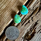 Turquoise earrings on a wooden surface with a quarter for scale.