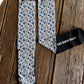 A pair of patterned crew socks laid flat on a rustic wooden surface, with one sock folded to show the black cuff and white text reading 'RED BARN SOCKS'. The socks have a blue, white, and gray floral/cactus-like pattern with black toe, heel, and cuff areas.