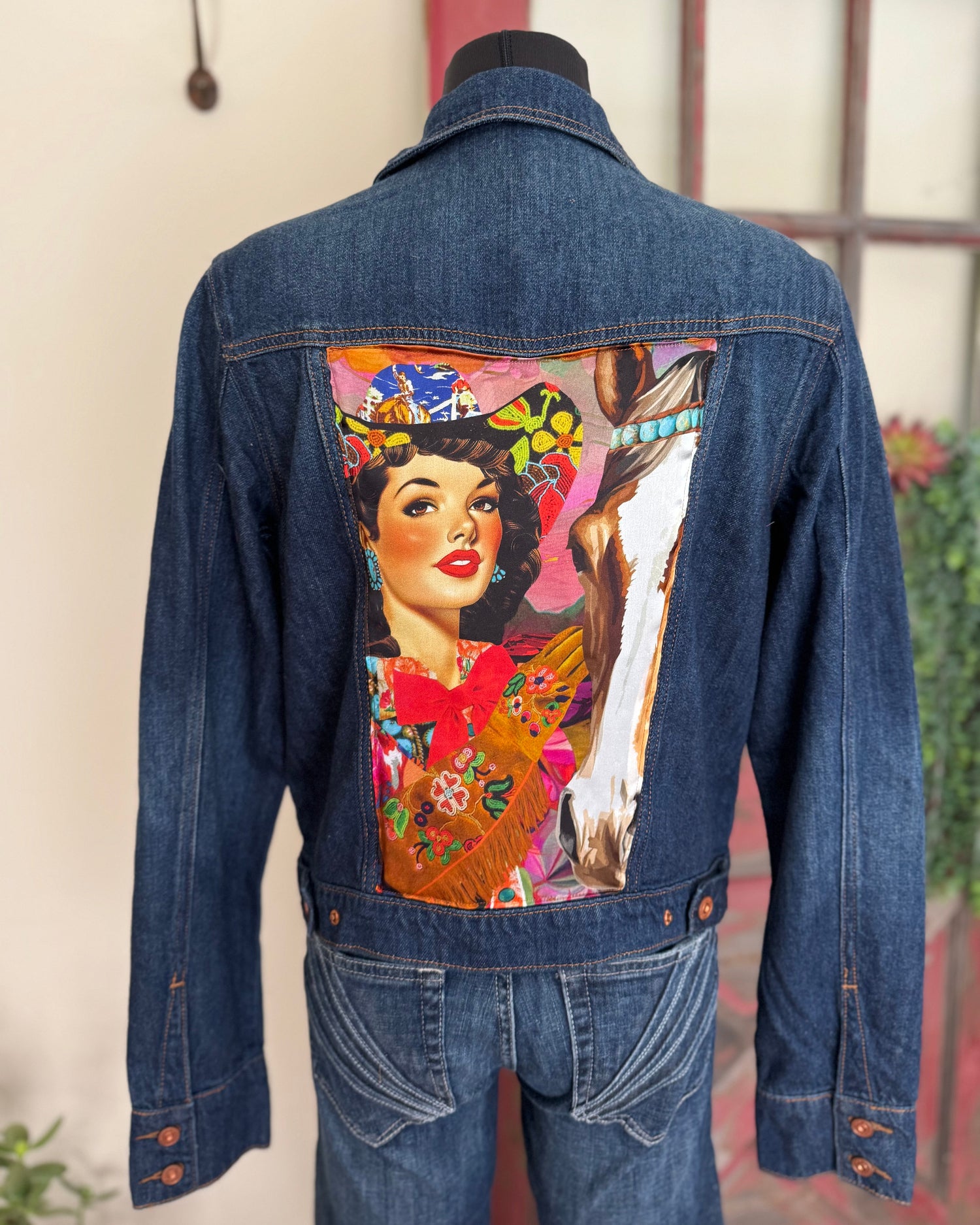 Denim jacket with a colorful graphic design on the back, featuring a woman and horse