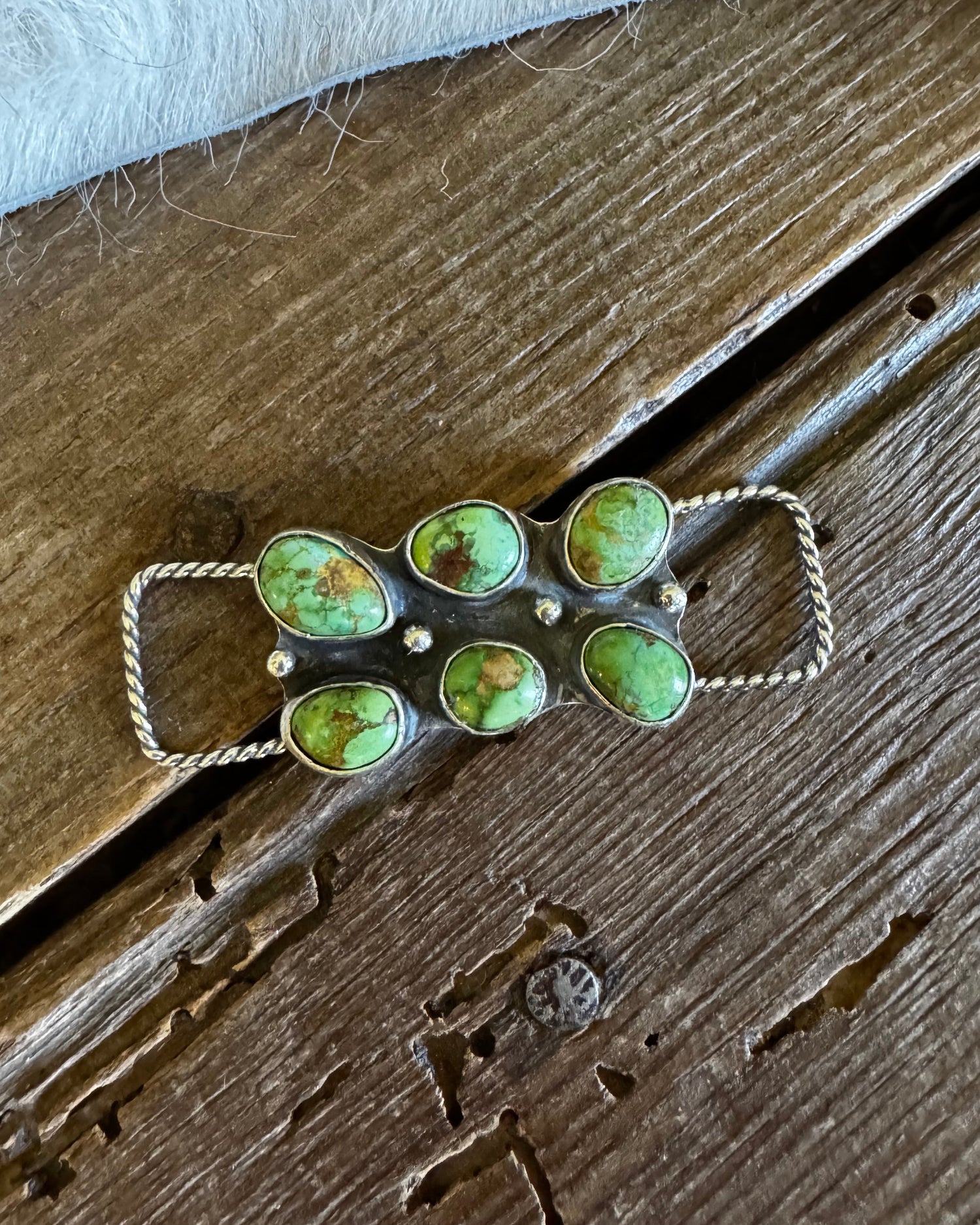 Jewelry with green stones on a wooden surface